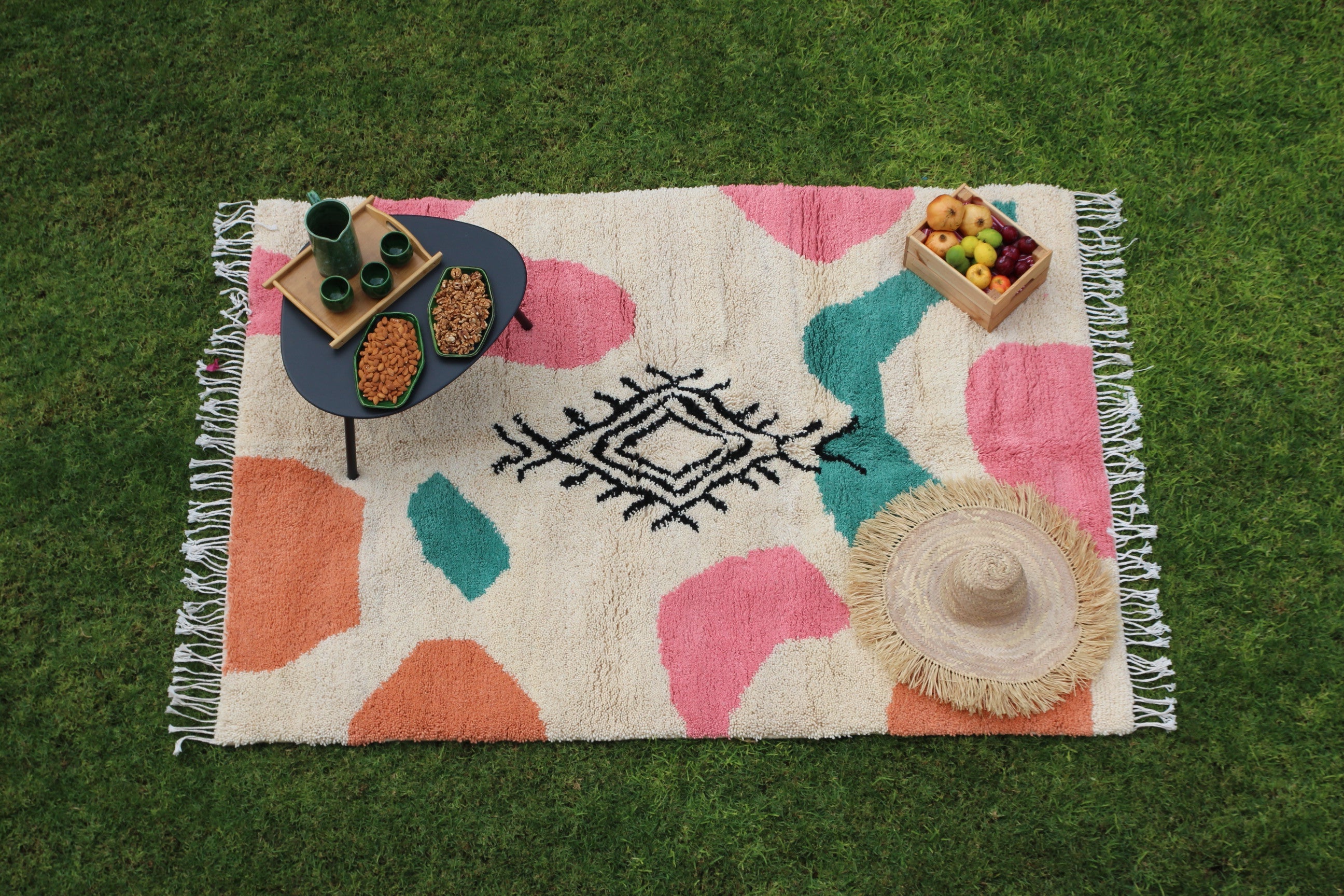 Colorful patterned rug with fringe on a grassy background