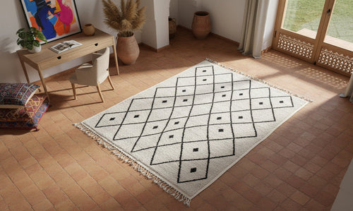 BENI OUARAIN rug with pillows and a small table on grass