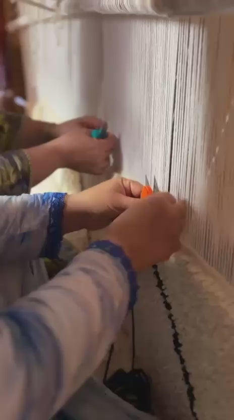 hand weaving a rug of natural wool on a traditional loom